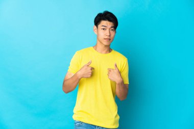 Mavi arka planda izole edilmiş genç bir Çinli kendini işaret ediyor.