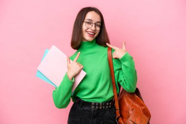 Pembe arka planda izole edilmiş genç Ukraynalı bir kadın baş parmak hareketi yapıyor.