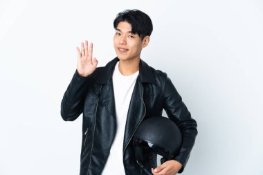 Motosiklet kasklı Çinli bir adam beyaz arka planda izole edilmiş mutlu bir ifadeyle selamlıyor.