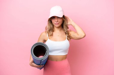 Genç sporcu kadın, elinde minder tutarken yoga derslerine gidiyor.