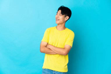 Young Chinese man isolated on blue background happy and smiling