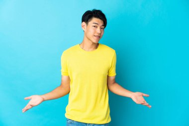 Young Chinese man isolated on blue background happy and smiling