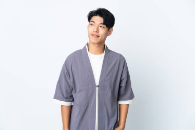 Genç Çinli bir adam beyaz arka planda izole edilmiş, yukarı bakarken bir fikir düşünüyor.