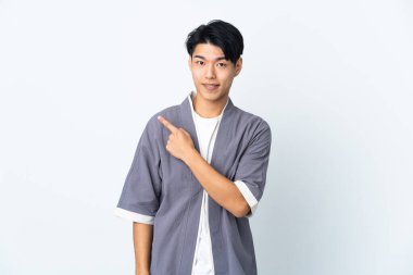 Beyaz arka planda izole edilmiş genç Çinli bir adam bir ürün sunmak için kenarı işaret ediyor.