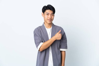 Beyaz arka planda izole edilmiş genç bir Çinli baş parmak hareketi yapıyor.