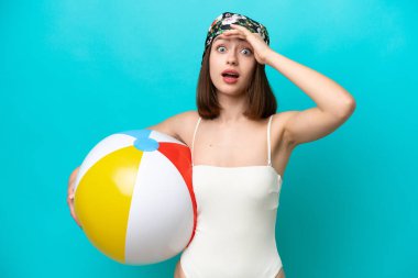 Mavi arka planda kumsal topu tutan genç Ukraynalı kadın yan tarafa bakarken sürpriz jest yapıyor.