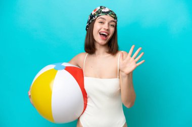 Mavi arka planda kumsal topu tutan genç Ukraynalı kadın parmaklarıyla beşi sayıyor.
