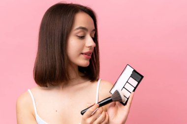 Genç Ukraynalı bir kadın pembe arka planda makyaj paletiyle izole edilmiş.