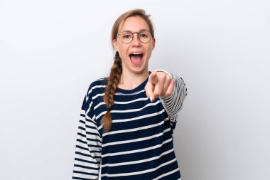 Beyaz arka planda izole edilmiş genç beyaz kadın şaşırmış ve ön tarafı işaret ediyor.