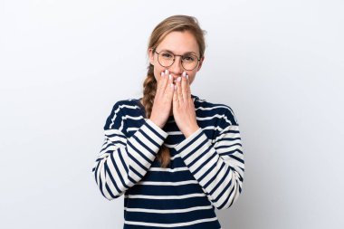 Beyaz arka planda izole edilmiş genç beyaz bir kadın mutlu ve gülümseyen elleriyle ağzını kapatıyor.