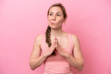 Pembe arka planda izole edilmiş genç beyaz kadın bir şeyler planlıyor.