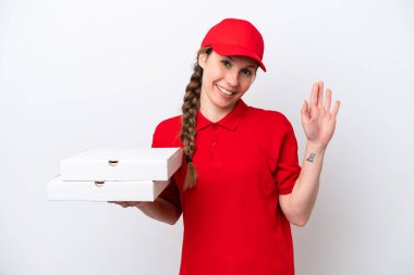 Pizza dağıtan kadın iş üniformalı beyaz arka planda izole pizza kutuları alıyor mutlu bir ifadeyle selamlıyor.