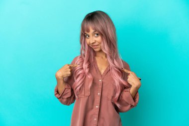 Pembe saçlı, mavi arka planda soyutlanmış, gururlu ve kendini beğenmiş genç bir ırk kadını.