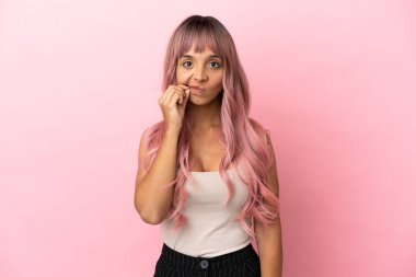 Pembe saçlı melez bir kadın. Pembe arka planda izole edilmiş. Sessizlik işareti gösteriyor.