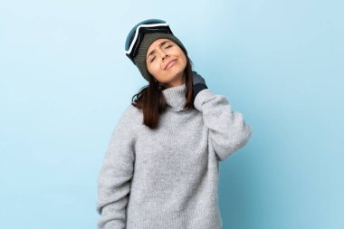 Karma kayakçı kız, snowboard gözlüklü, izole edilmiş mavi arka planda, boyun ağrısı olan..