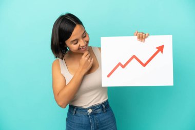 Mavi arka planda izole edilmiş genç bir ırk kadını elinde büyüyen bir istatistik okunun sembolü olan bir tabela tutuyor ve düşünüyor.