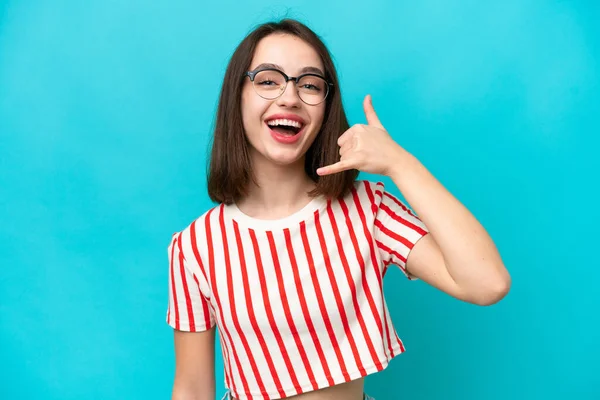 Mavi arka planda izole edilmiş genç Ukraynalı bir kadın telefon jesti yapıyor. Bana geri dönüş işareti ver.