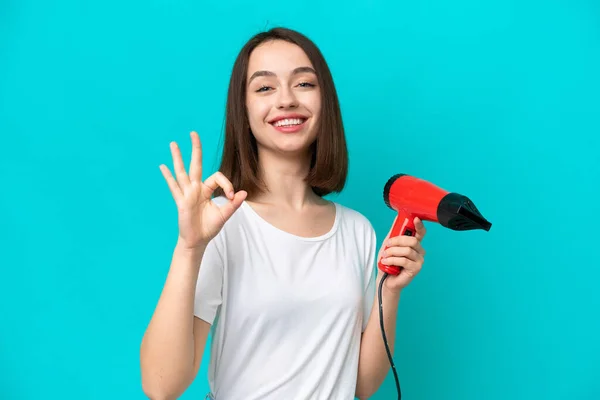 Young Ukrainian Holding Hairdryer Isolated Blue Background Showing Sign Fingers — Zdjęcie stockowe