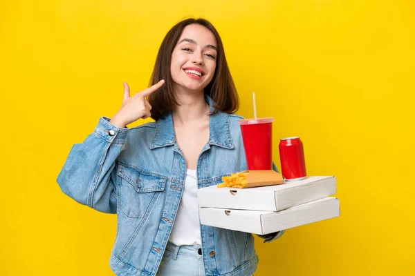 Young Ukrainian Woman Holding Fast Food Isolated Yellow Background Giving — Stock Photo, Image