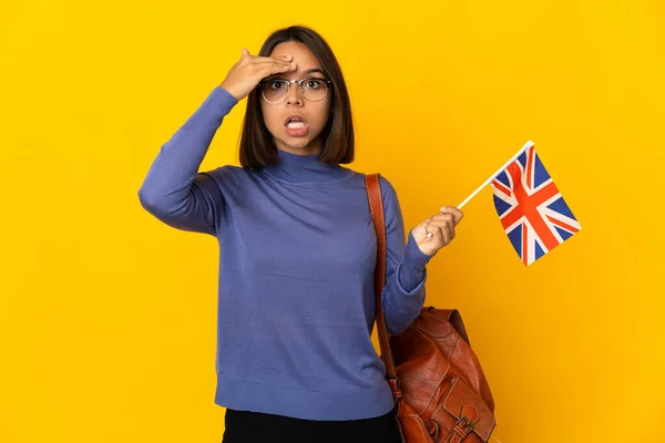 年轻的拉丁女子举着一面英国国旗 背景是黄色的 她意识到了什么 并打算解决这个问题 — 图库照片