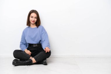 Young Ukrainian woman sitting on the floor isolated on white background laughing
