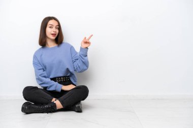 Genç Ukraynalı kadın, beyaz arka planda izole bir şekilde yerde oturuyor.