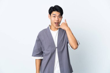 Beyaz arka planda izole edilmiş genç bir Çinli telefon hareketi yapıyor. Bana geri dönüş işareti ver.