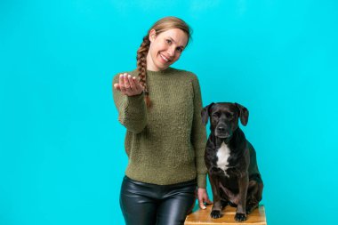 Köpeğiyle birlikte mavi arka planda izole edilmiş genç beyaz bir kadın, bizimle gelmesi için davet ediyor. Gelmene sevindim.