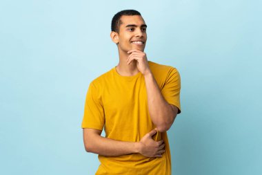 Afrika kökenli Amerikalı bir adam gülümserken yukarı bakıyor.