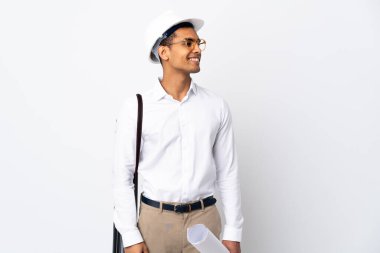 Miğferli ve elinde planlar olan Afrika kökenli Amerikalı bir mimar izole edilmiş beyaz bir arkaplanı inceliyor.