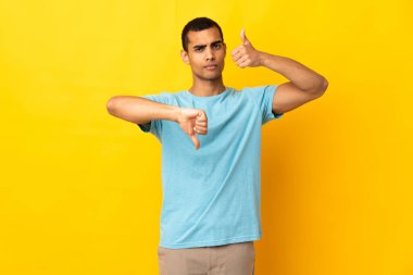 Tecrit edilmiş arka planda kalan Afro-Amerikalı bir adam iyiye-kötüye işaret yapıyor. Evet ya da hayır arasında kararsız