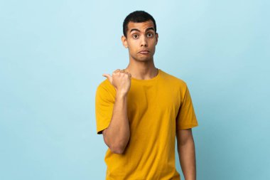 Afro-Amerikalı adam izole edilmiş arka planda mutsuz ve kenarı işaret ediyor.