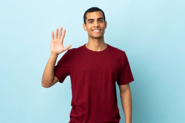 Afro-Amerikalı bir adam izole edilmiş arka planda mutlu bir ifadeyle selamlıyor.