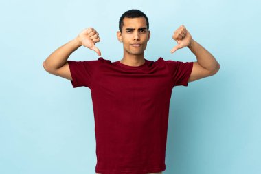 İzole edilmiş arka planda iki eliyle baş parmağını gösteren Afrikalı Amerikalı bir adam.