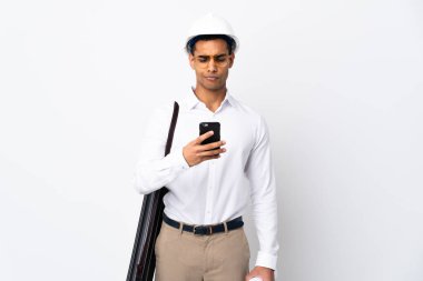 Miğferli ve elinde izole edilmiş beyaz arkaplan üzerinde planlar tutan Afrikalı Amerikalı mimar. Düşünüyor ve mesaj gönderiyor.