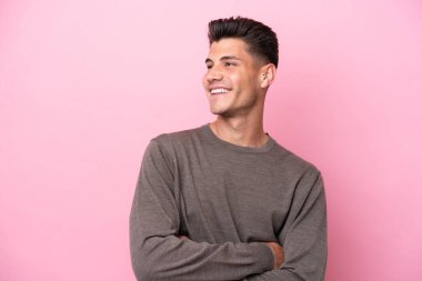 Pembe arka planda izole edilmiş genç beyaz adam mutlu ve gülümsüyor.