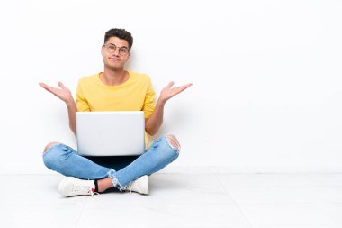 Genç adam, beyaz arka planda izole bir şekilde yerde oturuyor.