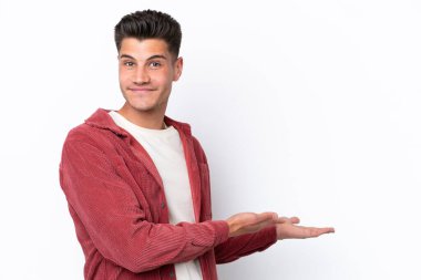 Beyaz arka planda soyutlanmış beyaz tenli genç adam davet edilmek için ellerini yana uzatıyor.