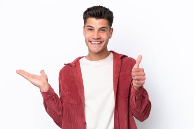 Beyaz arka planda izole edilmiş genç beyaz bir adam, bir ilan vermek ve onaylamak için avucunda hayali bir kopyalama alanı tutuyor.