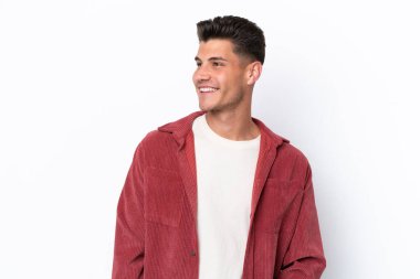 Beyaz arka planda izole edilmiş genç beyaz adam yana bakıyor ve gülümsüyor.