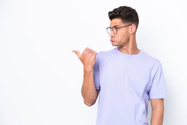 Beyaz arka planda izole edilmiş genç beyaz adam mutsuzdu ve kenarı gösteriyordu.