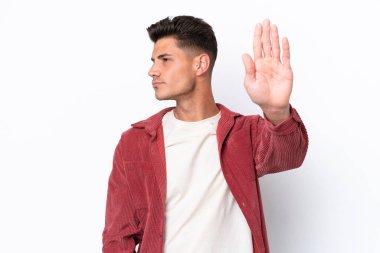 Beyaz arka planda izole edilmiş genç beyaz adam dur hareketi yapıyor ve hayal kırıklığına uğruyor.