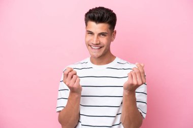 Pembe arka planda izole genç beyaz adam para hareketi yapıyor.
