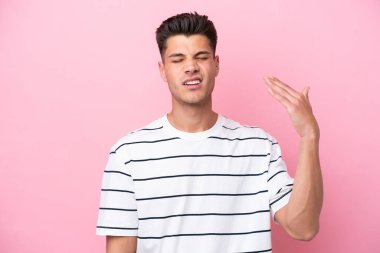 Pembe arka planda izole edilmiş, yorgun ve hasta bir ifadeyle genç beyaz bir adam.