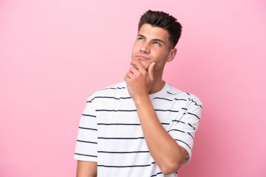 Genç beyaz adam pembe arka planda izole edilmiş ve yukarı bakıyor.