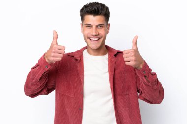 Beyaz arka planda izole edilmiş genç beyaz bir adam baş parmak hareketi yapıyor.