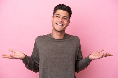 Pembe arka planda izole edilmiş genç beyaz adam mutlu ve gülümsüyor.