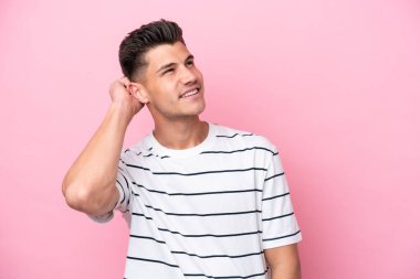 Pembe arka planda izole edilmiş genç beyaz bir adam bir fikir düşünüyor.