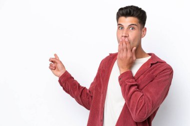 Beyaz arka planda izole edilmiş genç beyaz bir adam sürpriz bir ifadeyle işaret ederken...