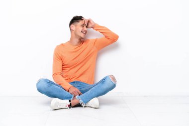 Beyaz arka planda izole bir şekilde yerde oturan genç adam bir şeyin farkına vardı ve çözüme niyetlendi.